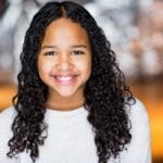 A young biracial girl with long curly brown hair.
