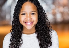 A young biracial girl with long curly brown hair.