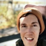 A young white man wearing an orange toque and sitting in a power wheelchair.