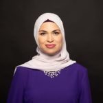 A Muslim woman in a purple dress and white hijab.