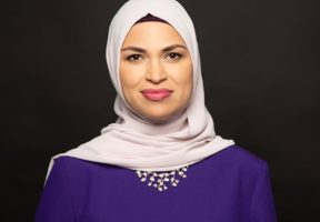 A Muslim woman in a purple dress and white hijab.