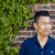 Photo of author Jack Wang--a middle-aged Chinese-Canadian man with short dark hair, wearing a dark blue button-up t-shirt. He stands against a brick wall and looks off to his left.