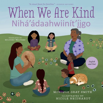 Book cover of When We Are Kind / Nihá’ádaahwiinít’íigo featuring two older women and four children of indigenous descent sitting in a circle with a drum